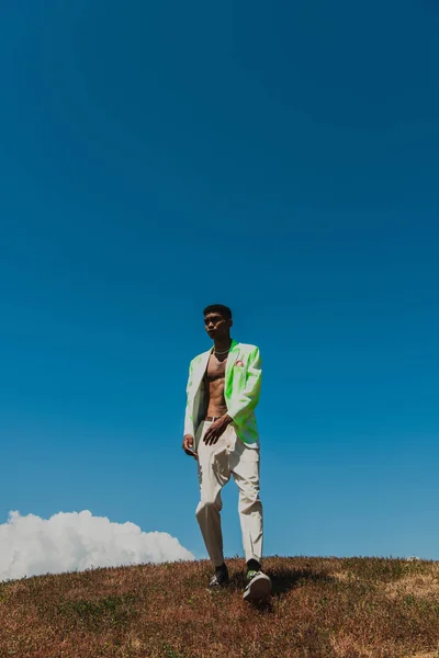 Full length african american man in trendy clothes walking in meadow — Stock Photo