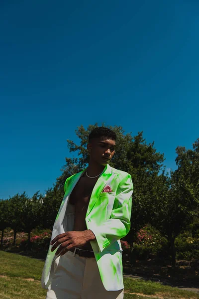 Young african american man in fashionable blazer near green trees — Stock Photo