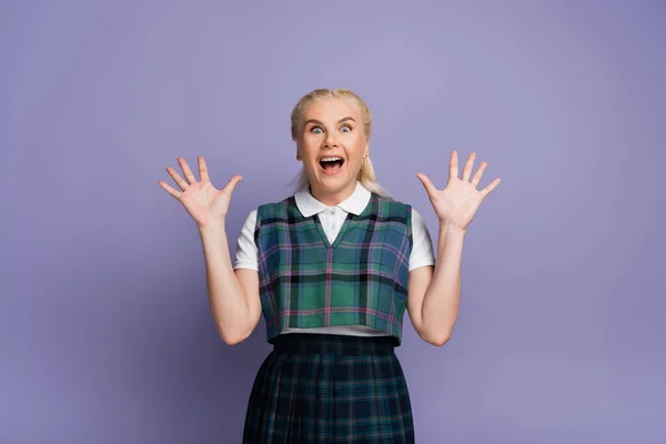 Amazed blonde student looking at camera on purple background — Stock Photo