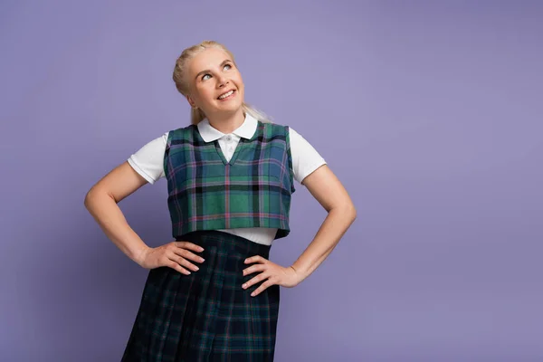 Dreamy and smiling blonde student looking away isolated on purple — Stockfoto