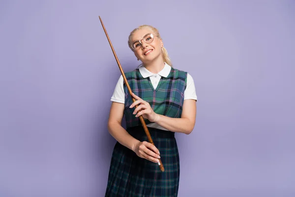 Smiling student in eyeglasses holding pointer on purple background — Stockfoto