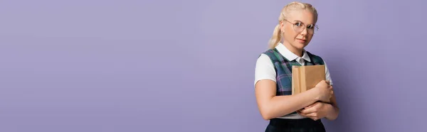 Blonde student in shirt and vest holding books isolated on purple, banner — Photo de stock