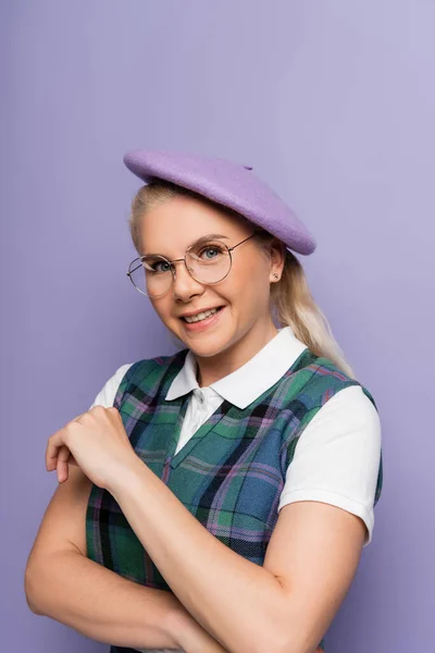 Portrait of blonde student in beret smiling at camera isolated on purple — Stock Photo