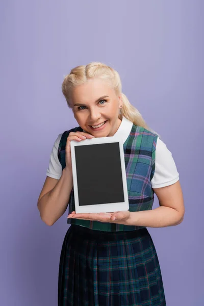 Smiling student holding digital tablet with blank screen isolated on purple — стоковое фото