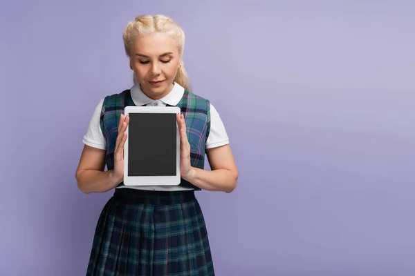 Student in uniform holding digital tablet with blank screen isolated on purple — Stock Photo