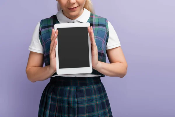 Обрізаний вид студента в картатій формі, що тримає цифровий планшет з порожнім екраном ізольовано на фіолетовому — стокове фото