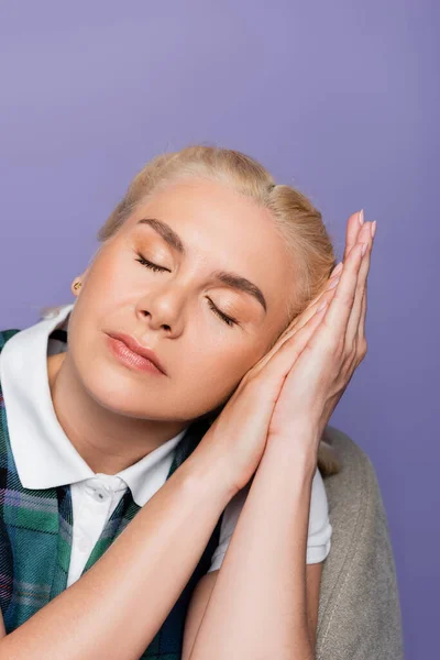 Blonde student closing eyes while sitting on armchair isolated on purple — Photo de stock