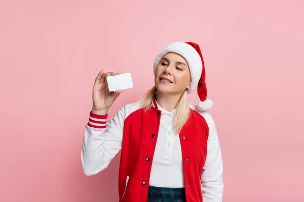 Blonde woman in red santa hat holding empty driving license isolated on pink - foto de stock