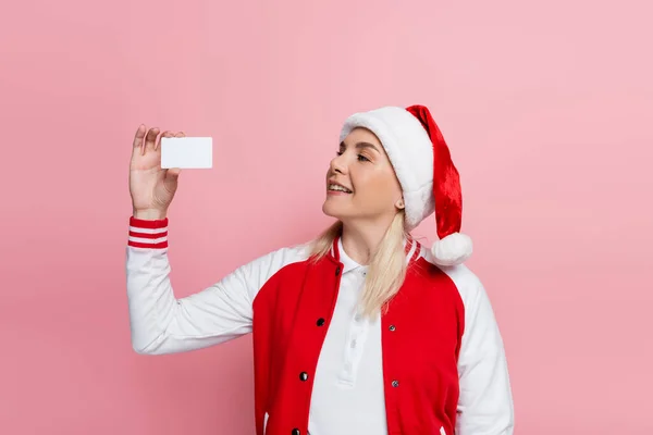 Smiling blonde woman in santa hat holding empty driving license isolated on pink — Stockfoto