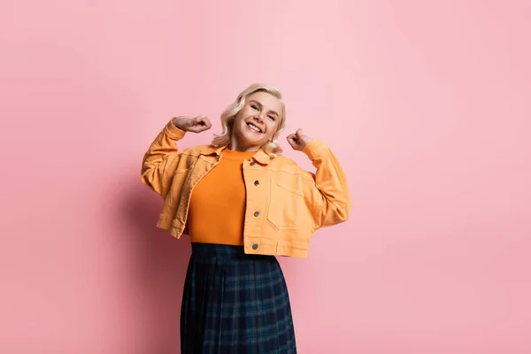 Happy woman stretching and looking at camera on pink background — Stock Photo