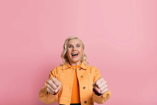 Amazed blonde driver looking at camera during driving course isolated on pink — Stock Photo