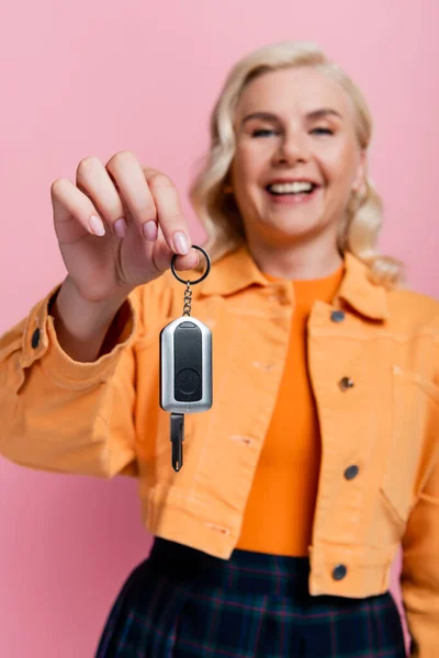 Car key in hand of blurred smiling driver isolated on pink - foto de stock