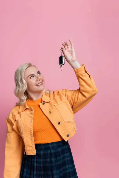 Smiling driver looking at car key isolated on pink — Foto stock