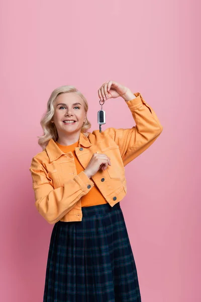 Pretty blonde woman holding car key isolated on pink — Fotografia de Stock