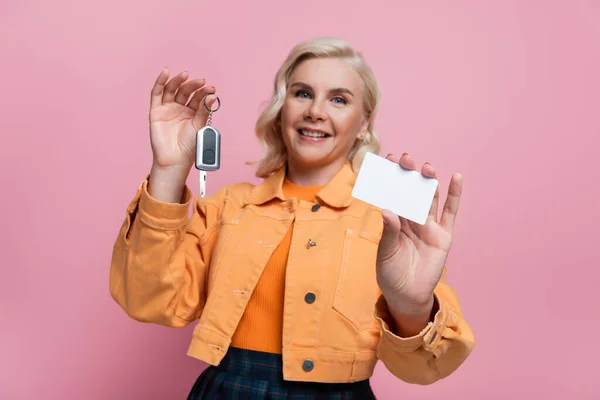 Car key and driving license in hands of blurred woman isolated on pink — стоковое фото