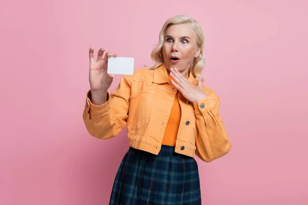 Shocked blonde woman holding empty driving license isolated on pink - foto de stock