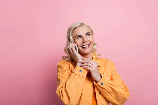 Happy blonde woman talking on mobile phone isolated on pink — Stock Photo