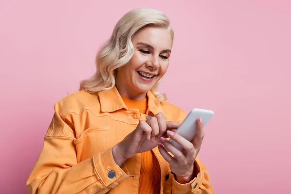 Pretty blonde woman using smartphone isolated on pink — стоковое фото