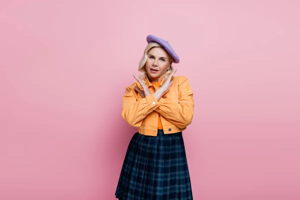 Stylish woman in beret showing stop sign at camera isolated on pink — стоковое фото