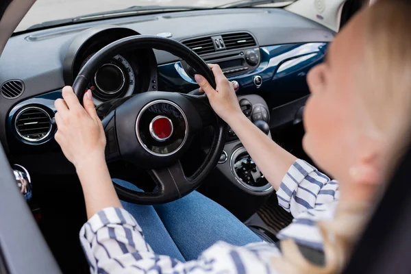Blurred woman holding steering wheel of car during driving course — Stockfoto
