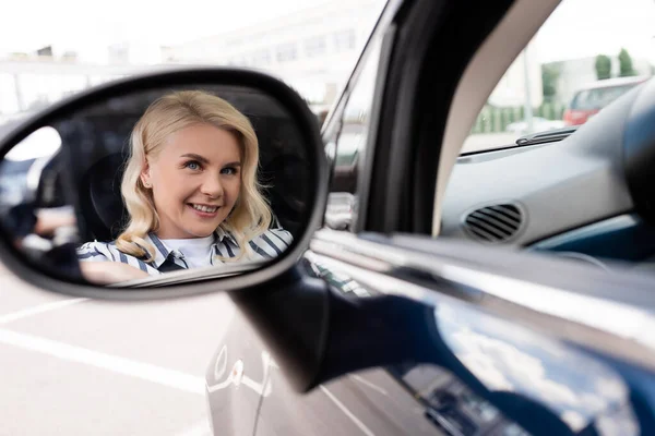 Positive woman reflecting in blurred car mirror — стоковое фото