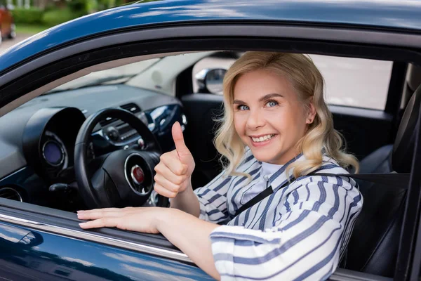 Smiling driver showing like during driving course in car — стоковое фото