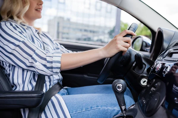 Cropped view of driver holding reeling wheel in car — Stockfoto