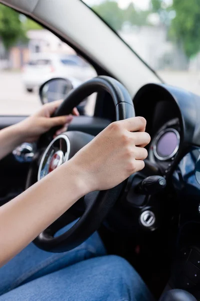 Cropped view of woman holding reeling wheel in car — стоковое фото