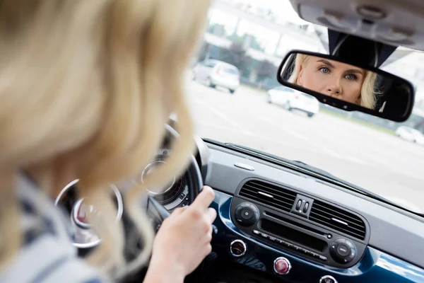 Blurred blonde driver reflecting in car mirror — Stock Photo