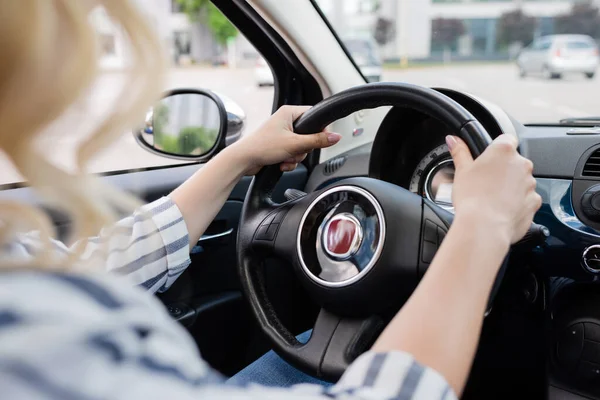 Cropped view of blonde driver holding steering wheel of car — Stockfoto