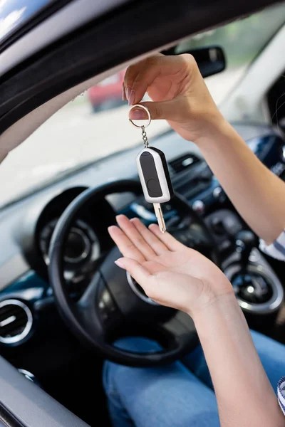 Cropped view of woman holding key while sitting on driver seat in car — Photo de stock