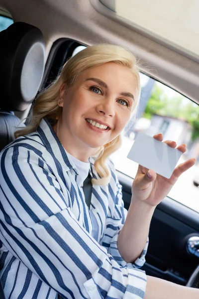 Cheerful woman holding empty driver license in car — стоковое фото