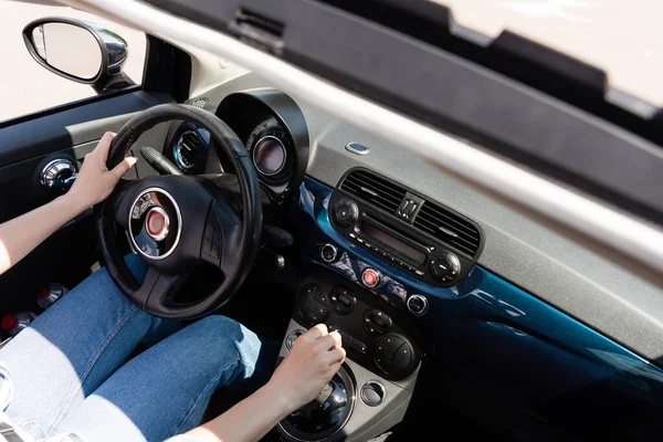 Cropped view of woman in jeans driving car — стоковое фото