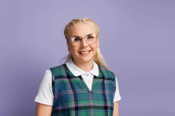 Portrait of smiling student in eyeglasses standing isolated on purple - foto de stock