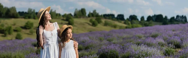Woman in straw hat hugging daughter in field with flowering lavender, banner — Foto stock