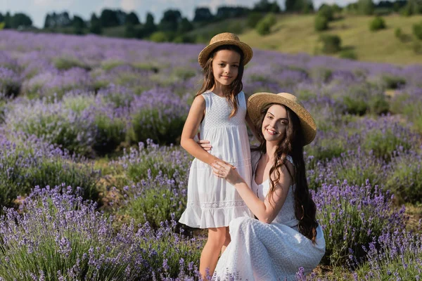 Счастливая женщина обнимает дочь и смотрит в камеру на лавандовом поле — стоковое фото