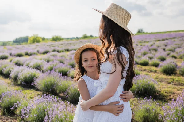 Happy child in white dress embracing mom in lavender field — Stock Photo