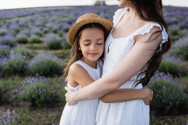 Усміхнена дівчина з закритими очима обіймає маму в лавандовому полі — стокове фото