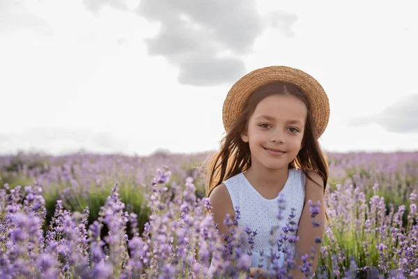 Happy child in straw hat looking at camera in lavender field — Stockfoto