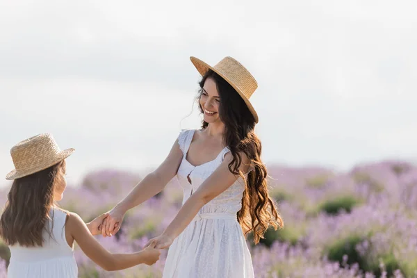 Brunette woman with long hair holding hands with daughter in countryside — Stock Photo