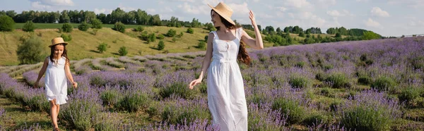 Woman and child in white dresses and straw hats walking in blooming meadow, banner — Foto stock