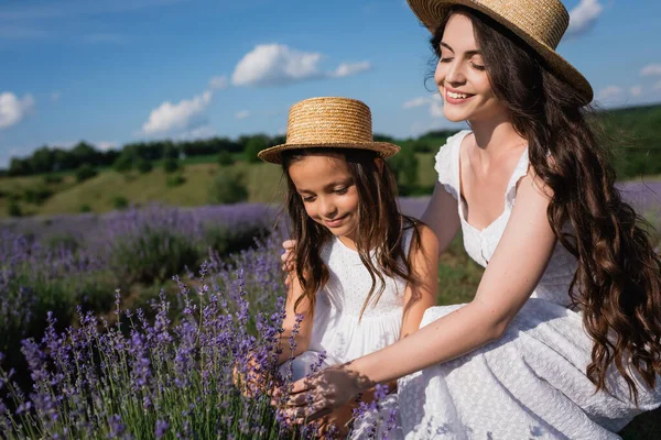 Женщина и ребенок с длинными брюнетками рядом с цветущей лавандой на лугу — стоковое фото