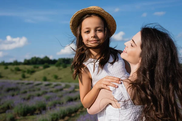 Щаслива жінка тримає дочку посміхається на камеру на відкритому повітрі — стокове фото