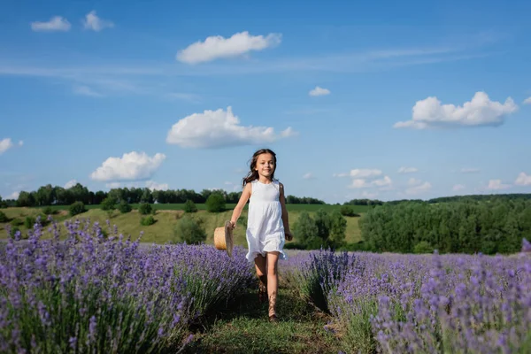 Full length of smiling girl in white summer dress walking in meadow of blooming lavender — Foto stock