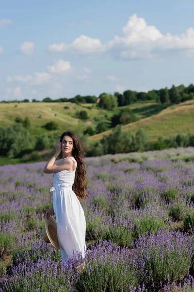 Красива жінка в білій сукні дивиться в поле з квітучою лавандою — стокове фото