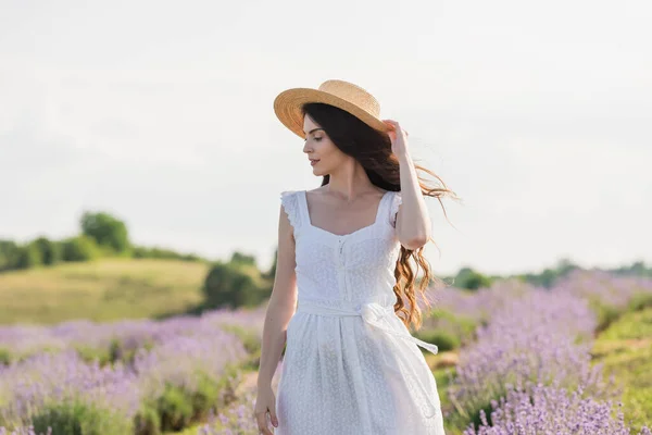 Woman in straw hat and white dress standing in blurred lavender field — Foto stock