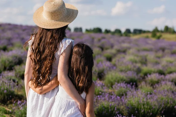 Back view of woman and girl with long hair embracing in field — Stockfoto