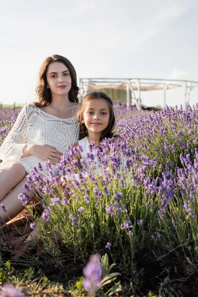 Happy girl with pregnant mother looking at camera in lavender meadow — Fotografia de Stock