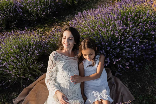 High angle view of pregnant woman and daughter sitting on blanket in lavender meadow — Stockfoto