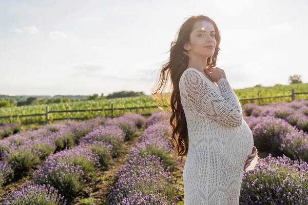 Pregnant woman with long hair smiling at camera in lavender field — Photo de stock